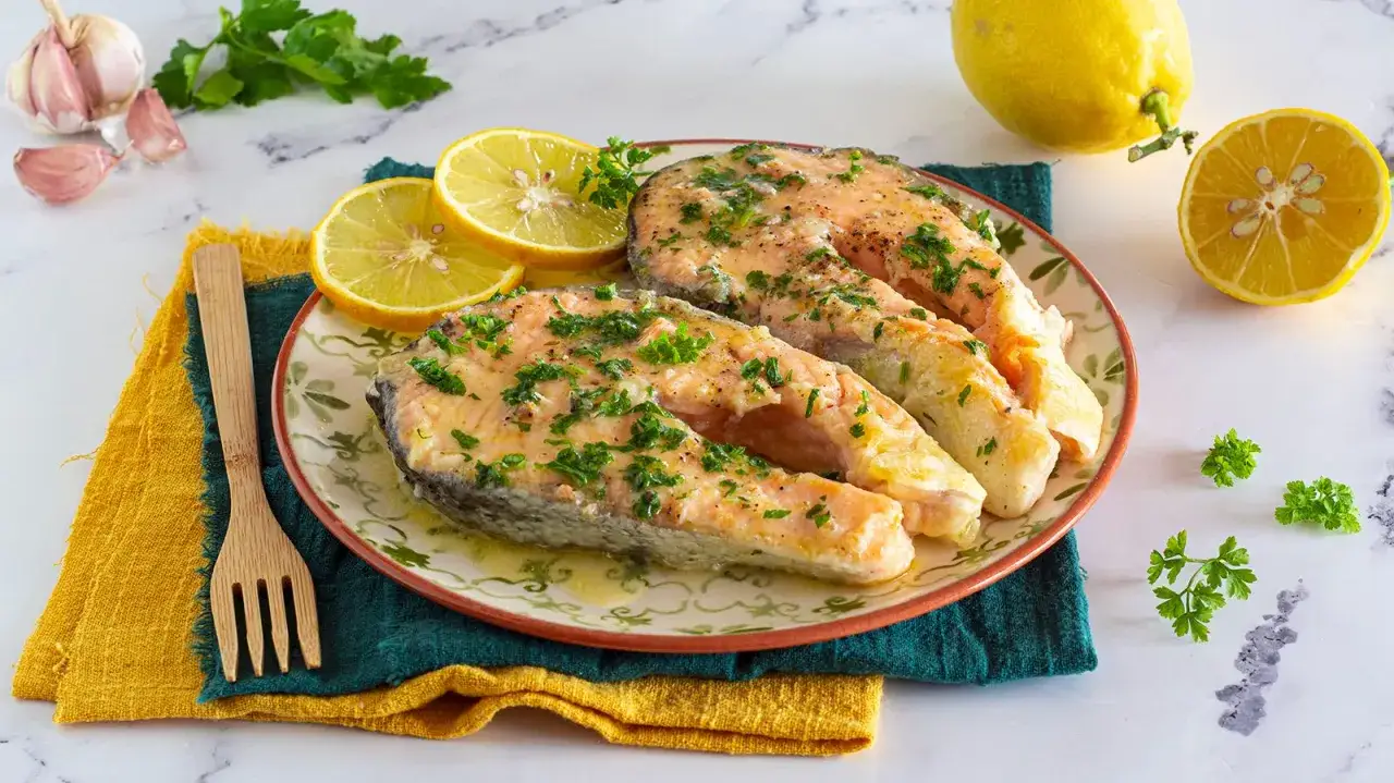 Succulento salmone in padella, guarnito con prezzemolo fresco e accompagnato da spicchi di limone. Un piatto semplice e gustoso.