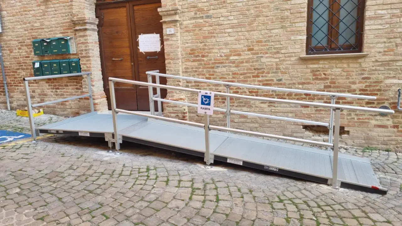 Rampa per superare le barriere architettoniche, conforme alla normativa vigente, con segnaletica per disabili.