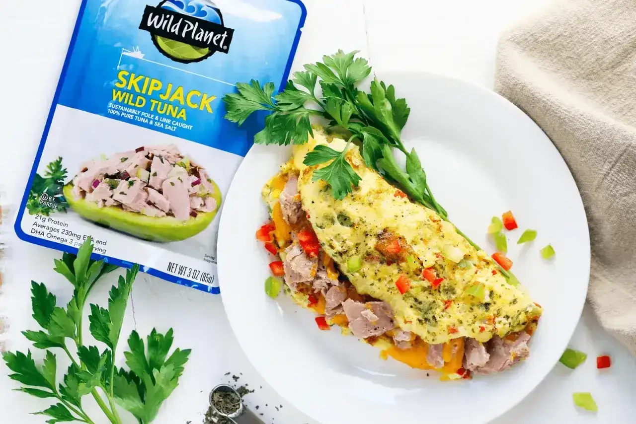 Pyszny omlet z tuńczykiem, papryką i ziołami, obok opakowania tuńczyka Wild Planet.