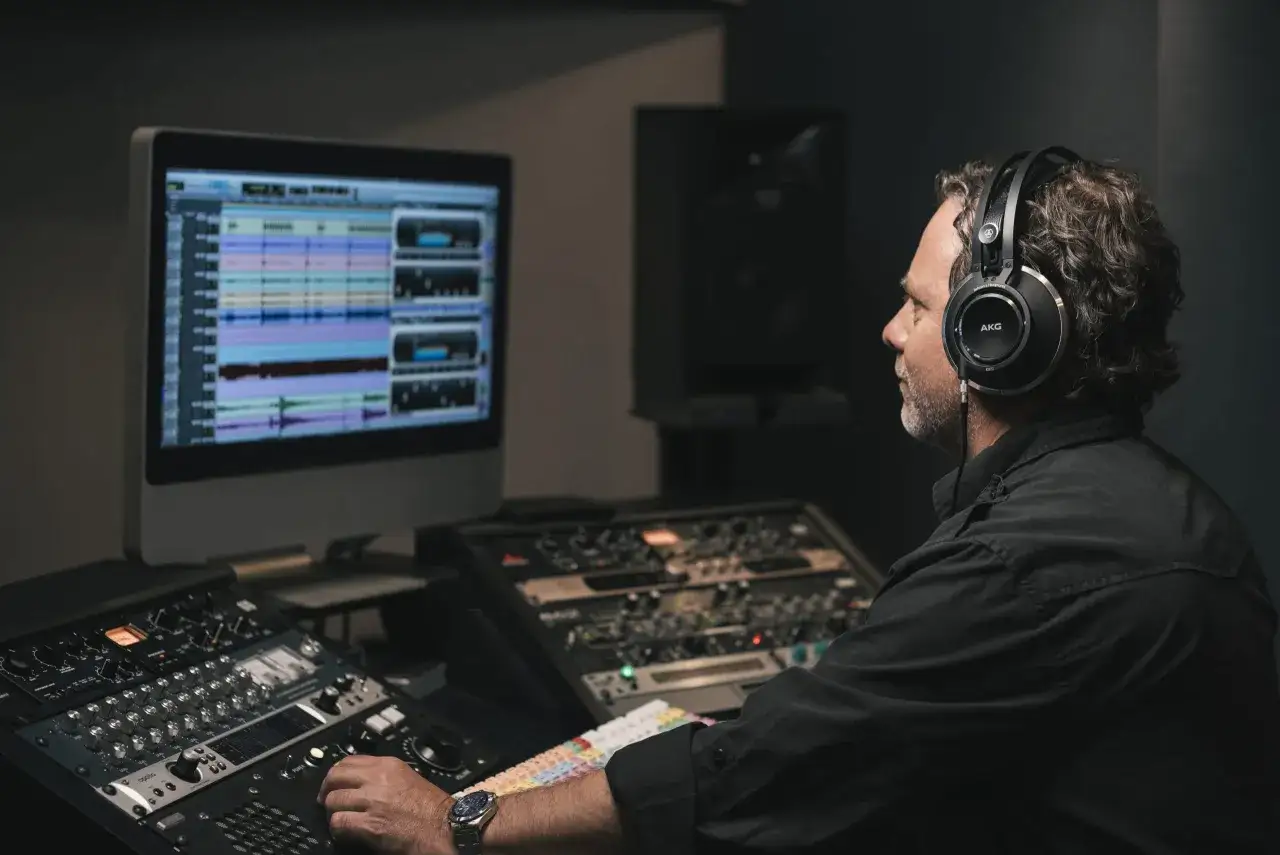 Producent muzyczny w słuchawkach AKG pracuje nad miksem, dodając efekt reverb, by nadać dźwiękom przestrzeni.