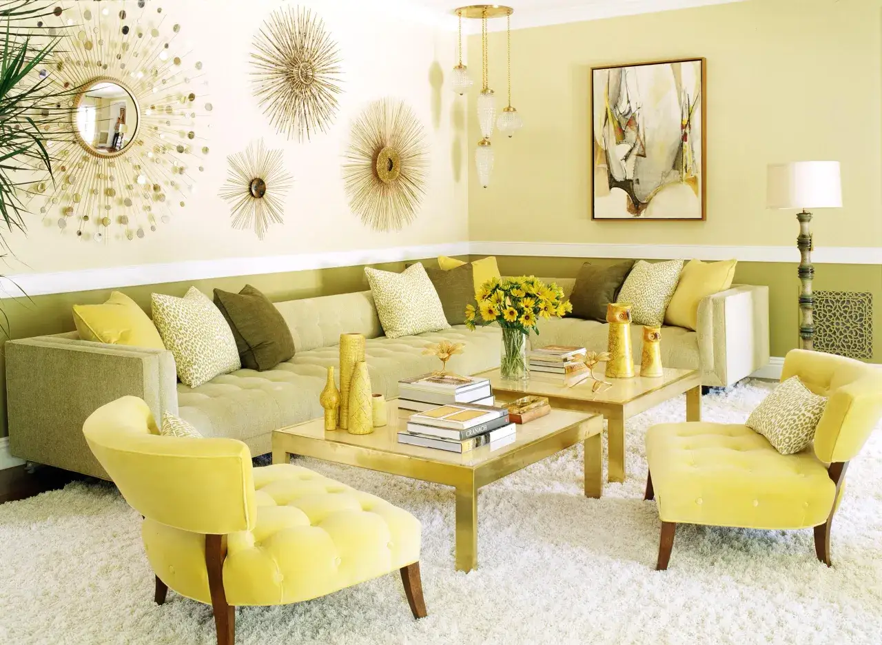 Ein Wohnzimmer in Gelb und Grün, mit einem Ecksofa, zwei Couchtischen, einem Spiegel und Wanddekorationen. Welche Farbe passt zu Gelb? Hier: Grün und Gold.