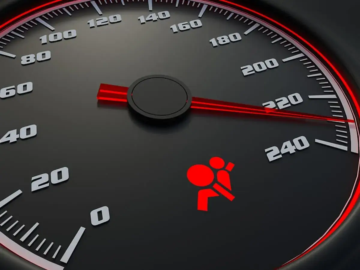 Tableau de bord d'une voiture avec un voyant rouge allum&eacute; indiquant un probl&egrave;me airbag. Le compteur de vitesse est visible.