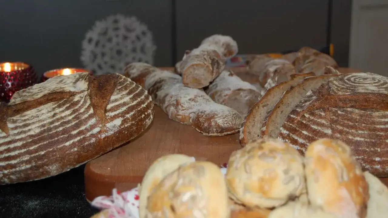 En härlig samling nybakade surdegsbröd och bullar. Doften av nybakat sprider sig i köket, perfekt för att baka med surdeg.