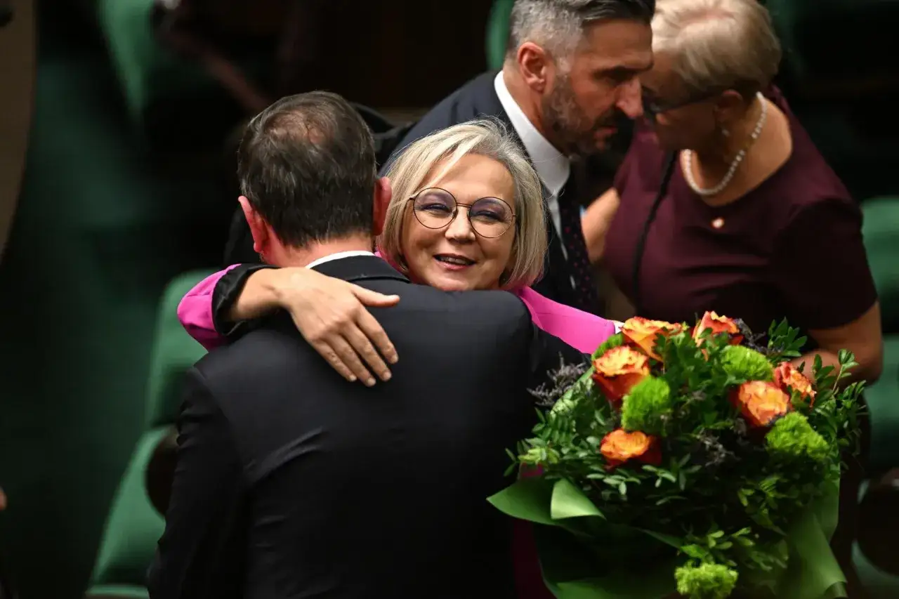 Dorota Niedziela, posłanka, uśmiecha się, obejmując kolegę. Obok bukiet kwiatów.