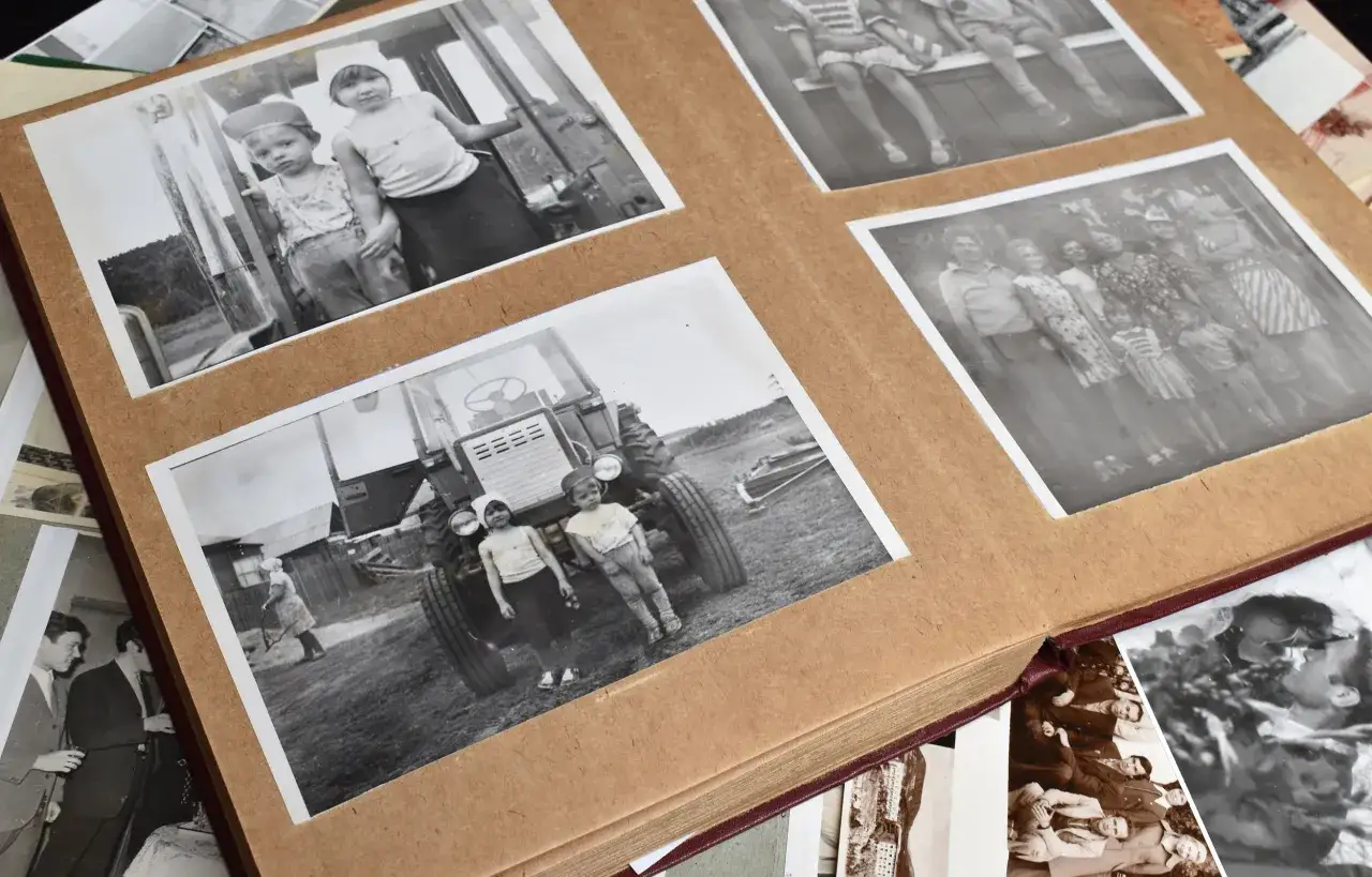 Stare fotografie w albumie, świadectwo digitalizacji zdjęć. Dzieci przy traktorze, rodzina na wsi, młodzi mężczyźni na przyjęciu.