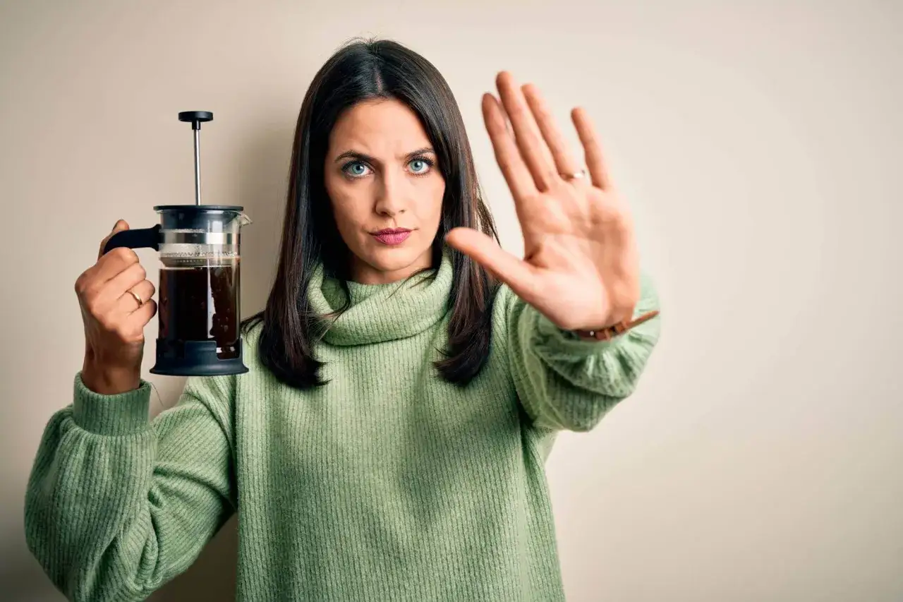 Mujer con cafetera de émbolo y mano extendida, diciendo