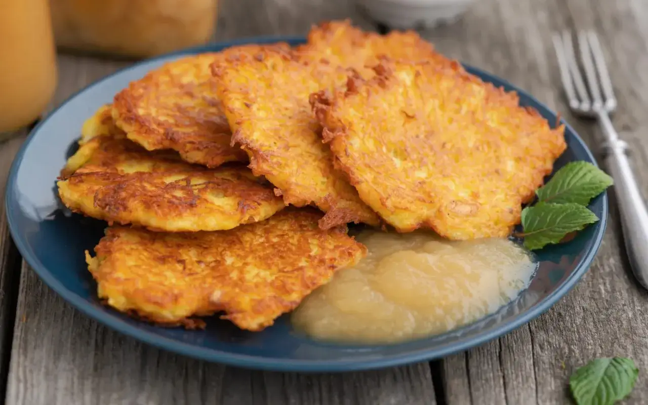Goldbraune Kartoffelpuffer auf blauem Teller mit Apfelmus. Ein köstliches Kartoffelpuffer Rezept für Genießer.