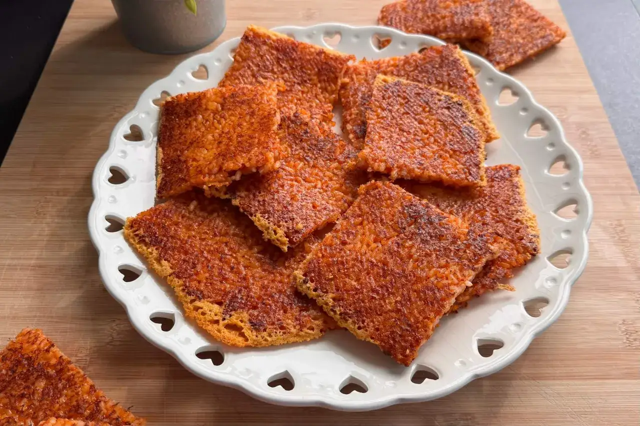 Croccanti quadretti di riso al forno, dorati e invitanti, serviti su un piatto bianco decorato con cuoricini.