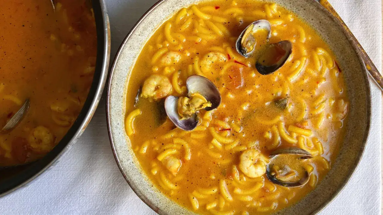Un plato humeante de fideos a la cazuela con gambas y almejas, un festín para los sentidos.