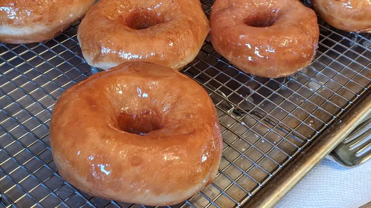 Frisch gebackene, glasierte Donuts auf einem Gitter. Ein perfektes Donuts Rezept f&uuml;r s&uuml;&szlig;e Momente.