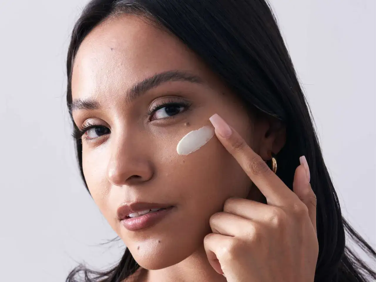 Donna applica delicatamente il primer sul viso, preparandolo per il trucco.
