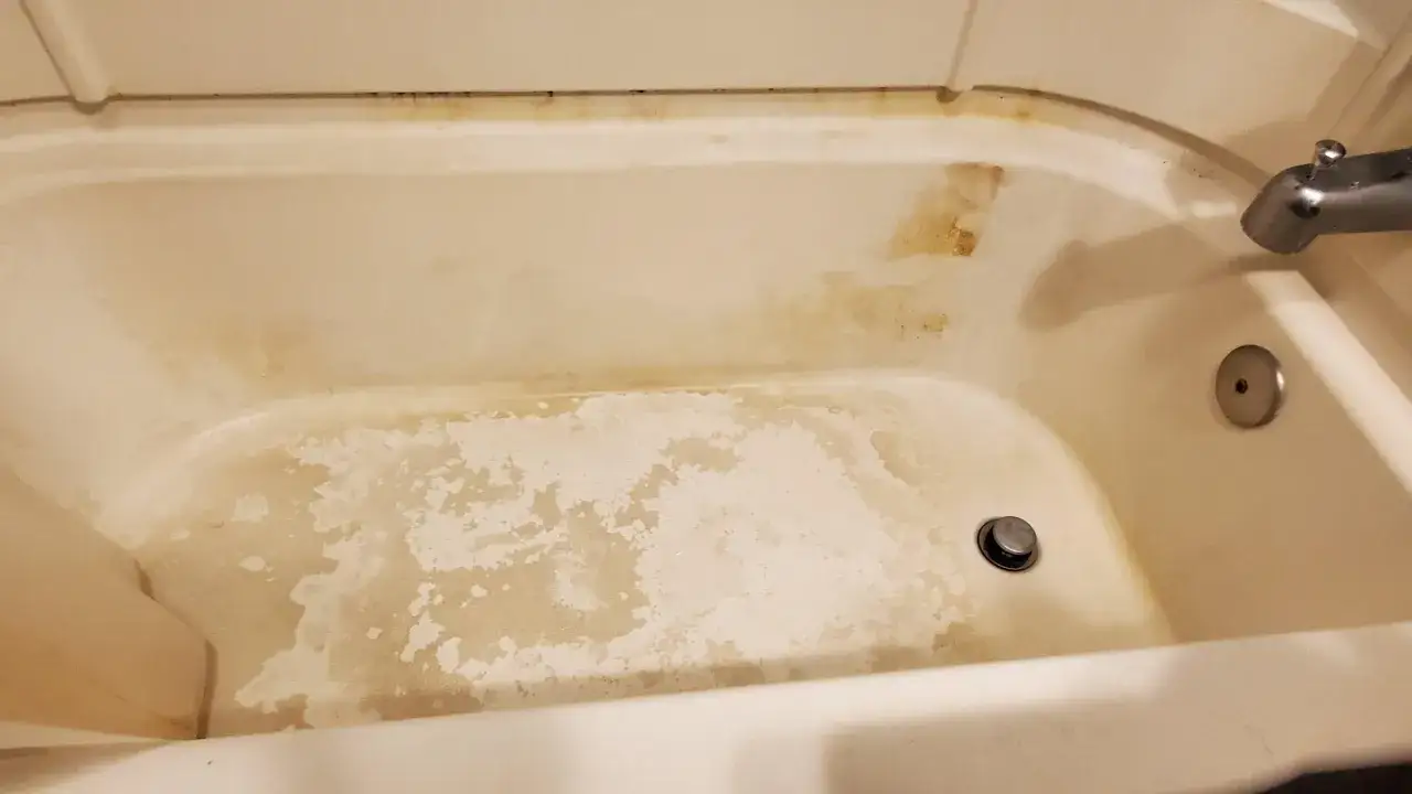 Intérieur d'une baignoire en acrylique montrant une importante trace jaune et des taches d'eau dure.
