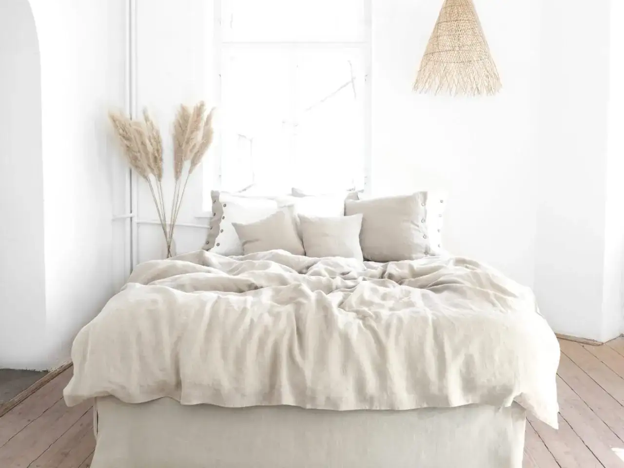 Ein helles Schlafzimmer mit einem Bett, das mit Leinen bezogen ist. Die Vorteile von Leinen sind seine Atmungsaktivität und Langlebigkeit, Nachteile können der Preis und das Knitterverhalten sein.