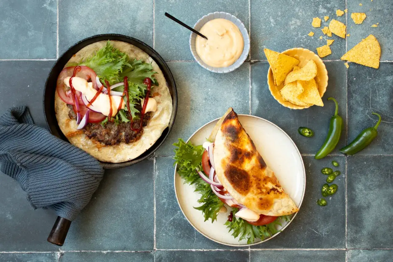 Enkla lunch recept med saftiga hamburgare i tortillabröd, serverade med nachos, jalapeños och en krämig sås.