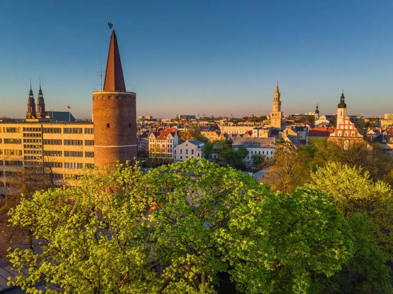 Opole atrakcje: Wieża Piastowska i ratusz na tle wiosennej zieleni.