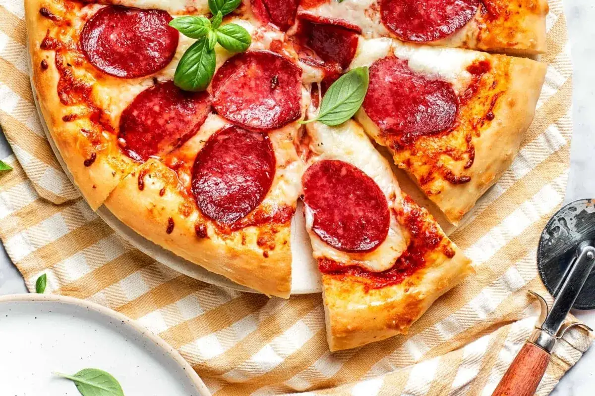 Pyszna pizza pepperoni z ciągnącym serem i świeżą bazylią, gotowa do podania.