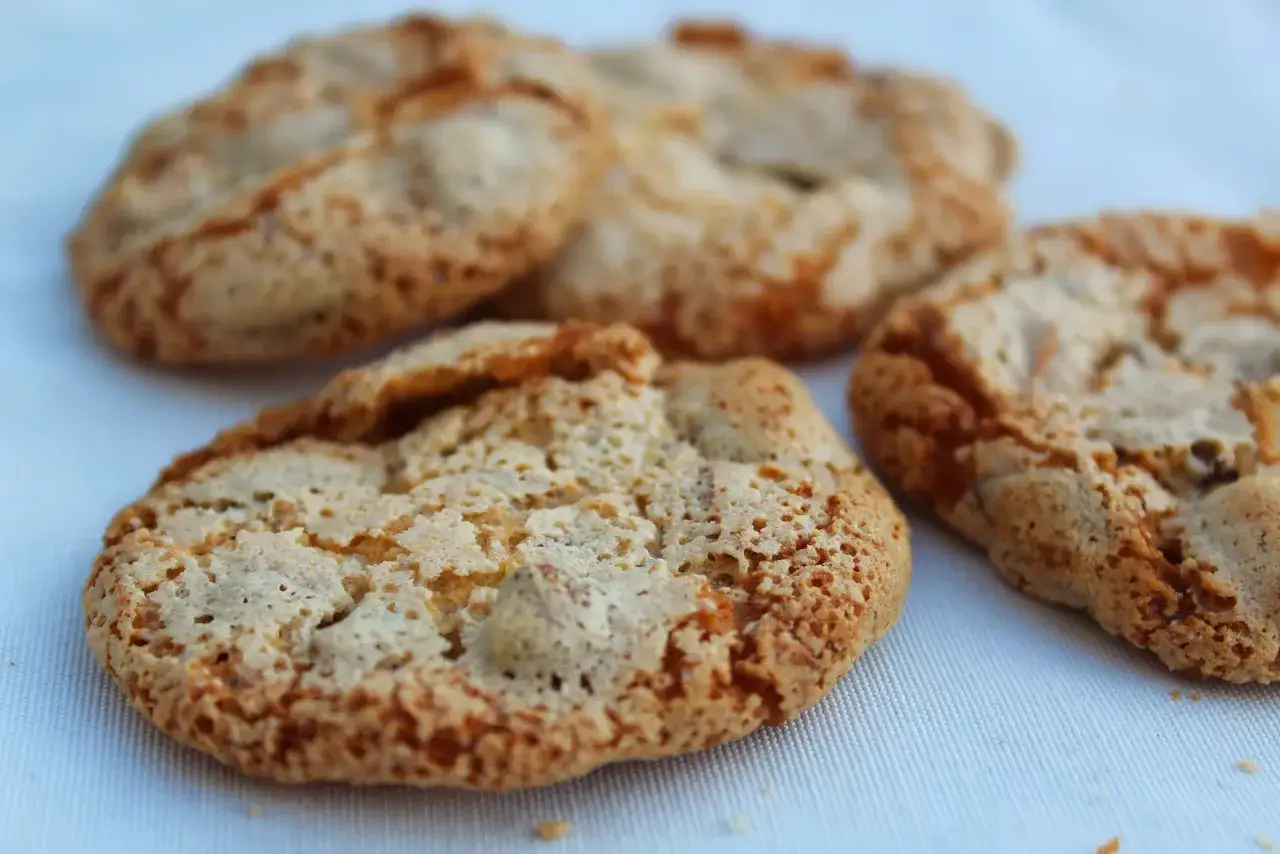 Quatre croquants aux amandes dorés et texturés, posés sur un tissu blanc.