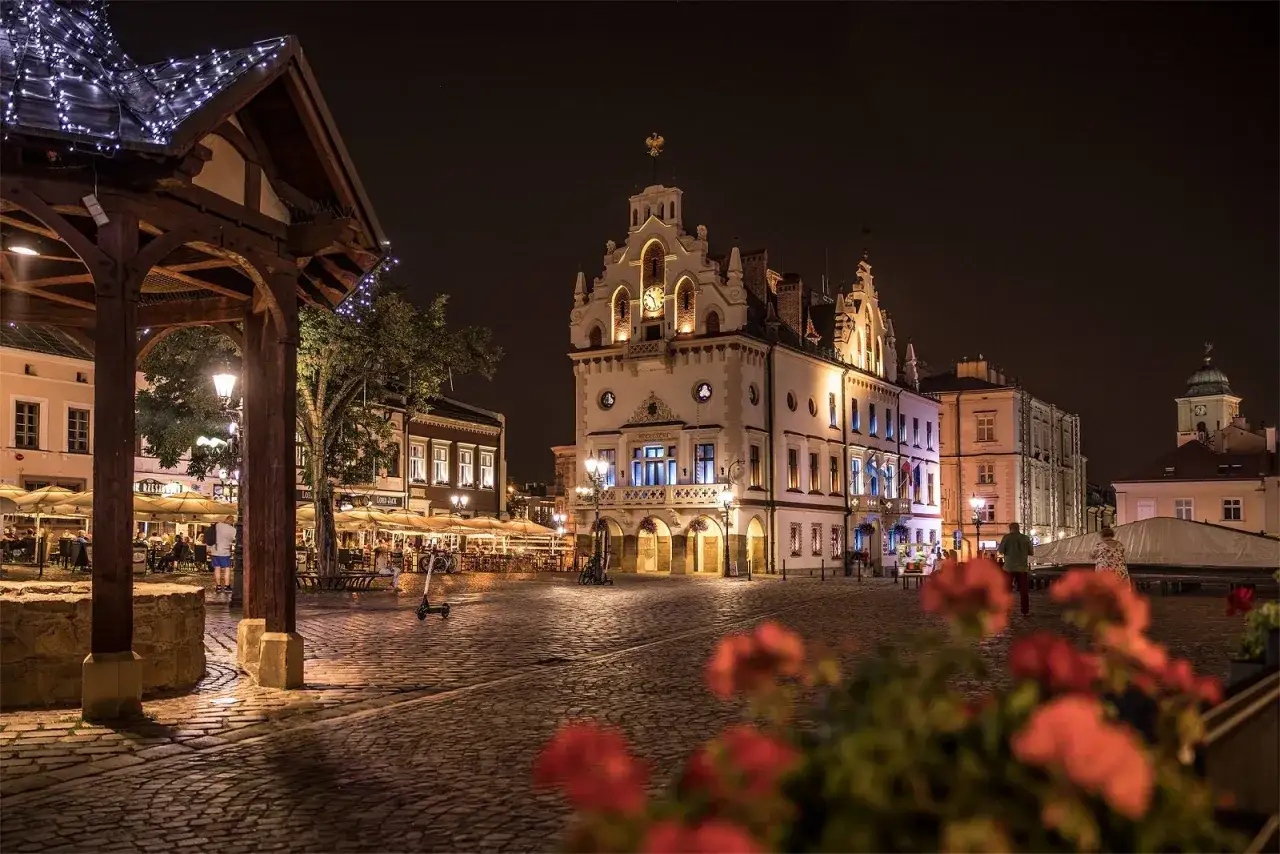 Rynek w Rzeszowie nocą, z ratuszem w tle. To miejsce, z którego słynie Rzeszów, tętni życiem wieczorem.