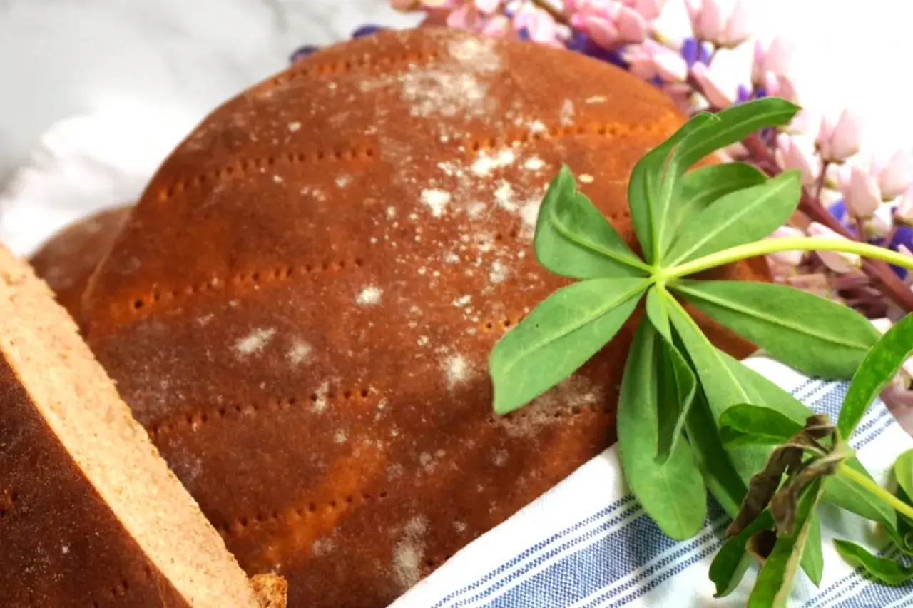 H&auml;r &auml;r ett h&auml;rligt r&aring;gkakor recept! En rund, m&ouml;rkbrun r&aring;gkaka med prickar och lite mj&ouml;l p&aring;, bredvid en bit av en annan kaka. Gr&ouml;na blad och rosa lupiner ger en somrig k&auml;nsla.