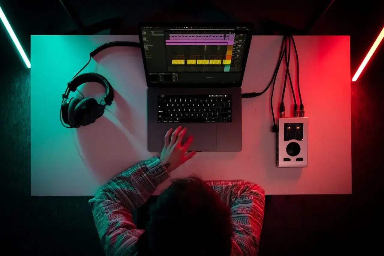 Un producteur de musique cr&eacute;e des sons sur son ordinateur, avec des &eacute;couteurs et une interface audio.