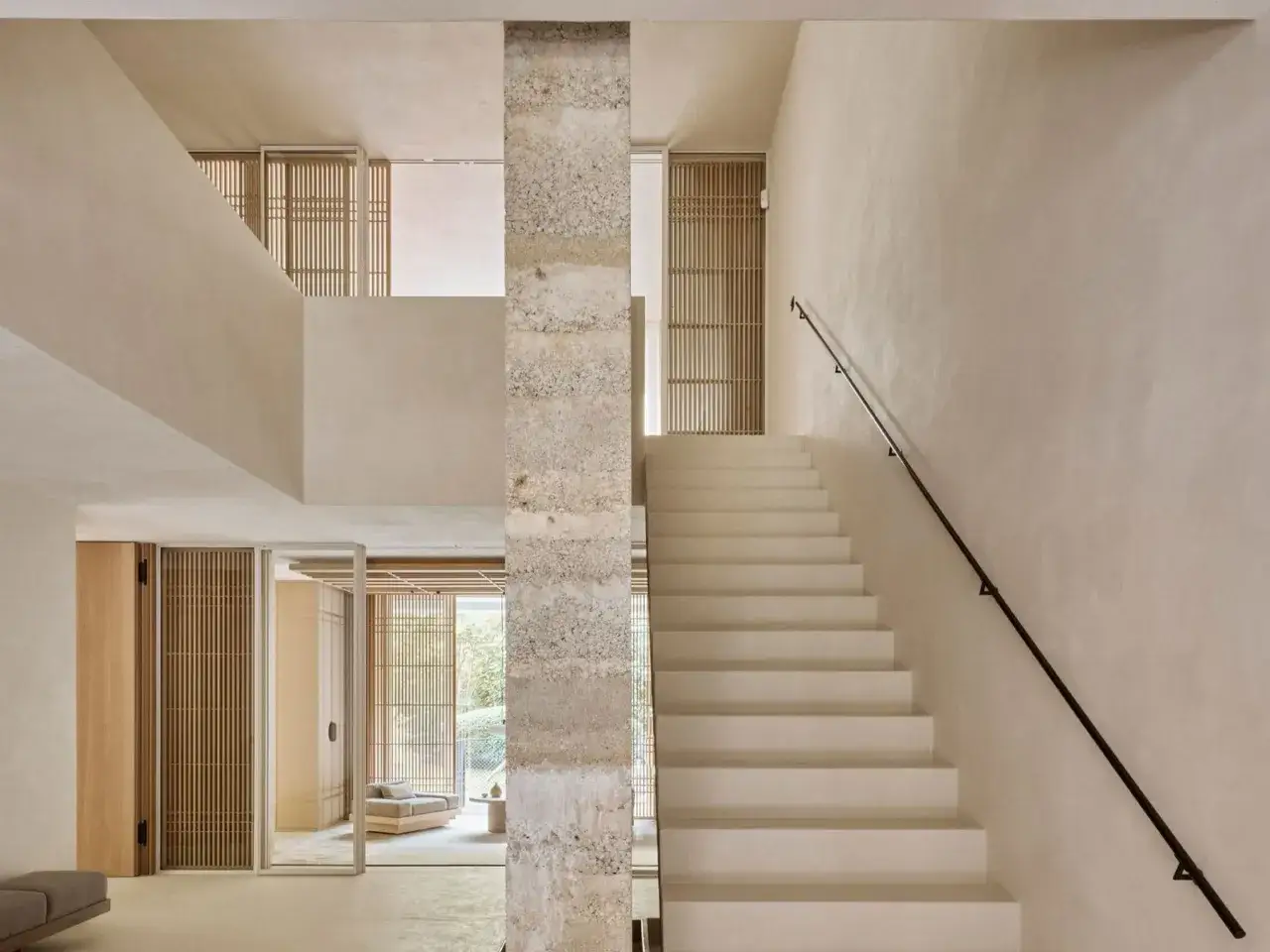 Escalera moderna con peldaños de hormigón pulido, ideal como materiales para forrar escaleras. Paredes de estuco y detalles en madera.