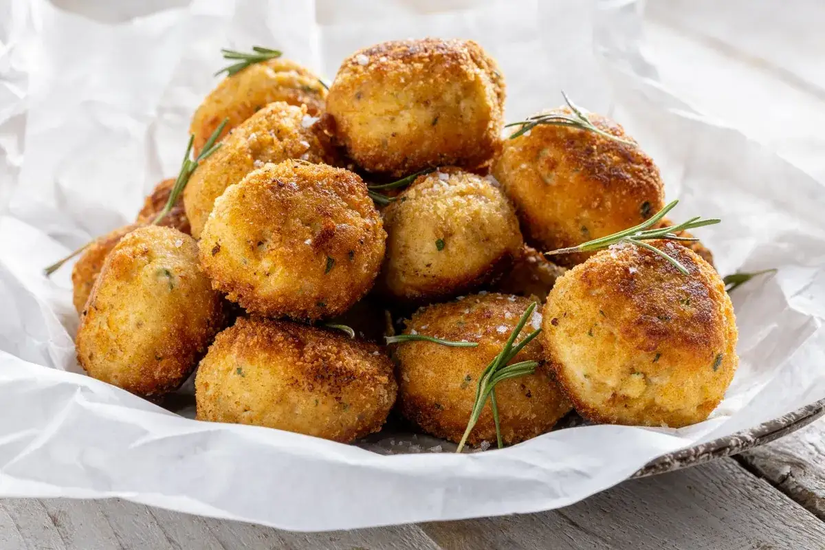 Un mucchio invitante di polpette in bianco, dorate e croccanti, guarnite con rosmarino fresco e sale grosso.