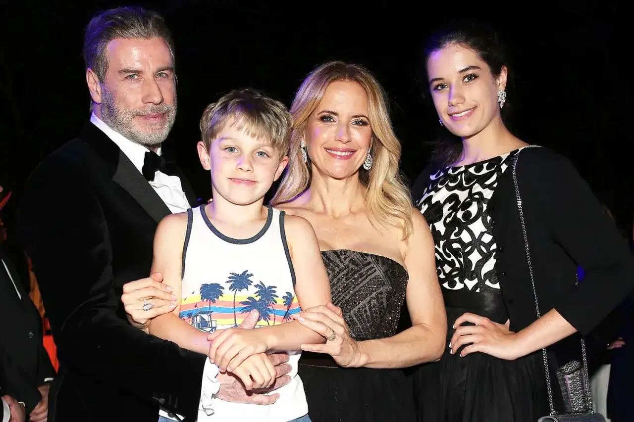 John Travolta med familj. Han bär en svart sammetskostym, sonen en färgglad tröja, hustrun en svart klänning och dottern en svartvit topp med kofta.