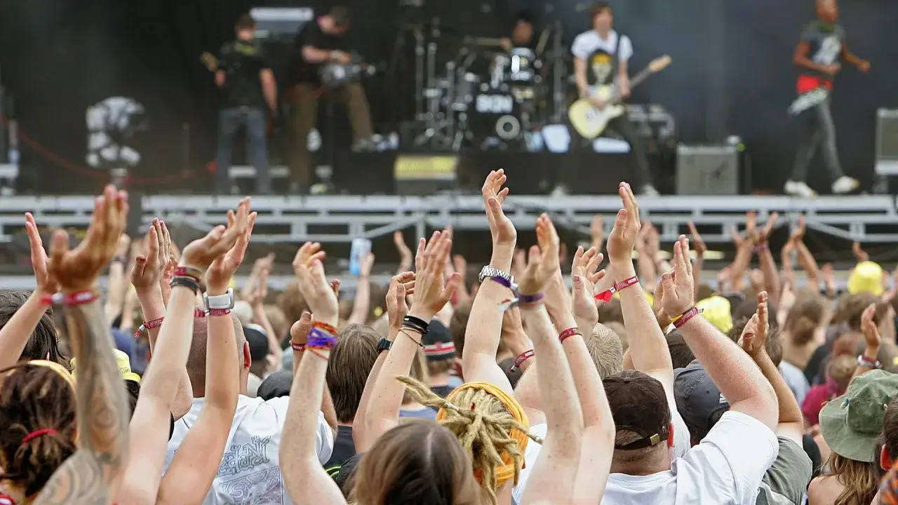 Menschen jubeln bei einem Konzert. Die Band spielt auf der B&uuml;hne, die Musikrichtung passt zum Hurricane Festival.