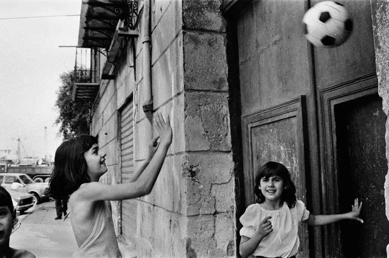 Letizia Battaglia giovane cattura due bambine che giocano a pallone per strada, un momento di gioia spensierata.