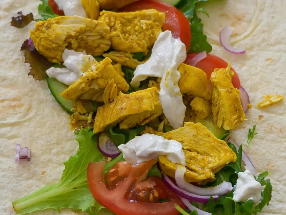 Un chawarma poulet savoureux, garni de poulet épicé, de légumes frais et d'une sauce crémeuse, prêt à être dégusté.