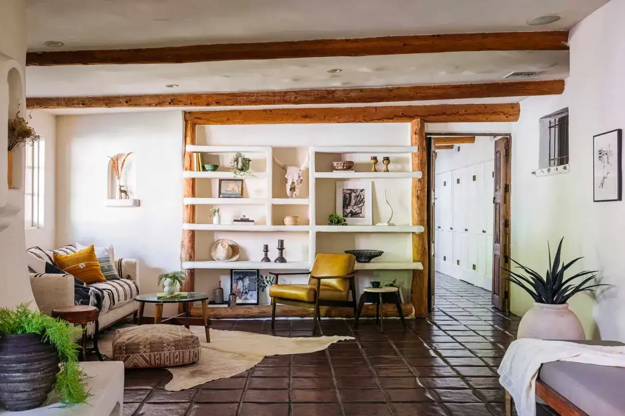 A cozy living room with a rustic vibe, featuring a sofa, armchair, and built-in shelves, embodying a warm Mediterranean interior design.