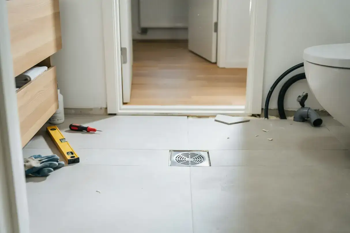 Verktyg för att byta våtrumsmatta ligger redo vid golvbrunnen.
