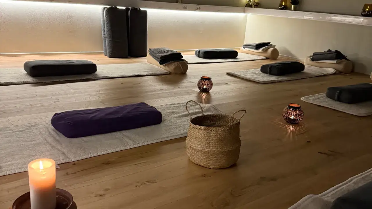 Förberedd för morgonmeditation. Mattor, kuddar och levande ljus skapar en lugn atmosfär på trägolvet.