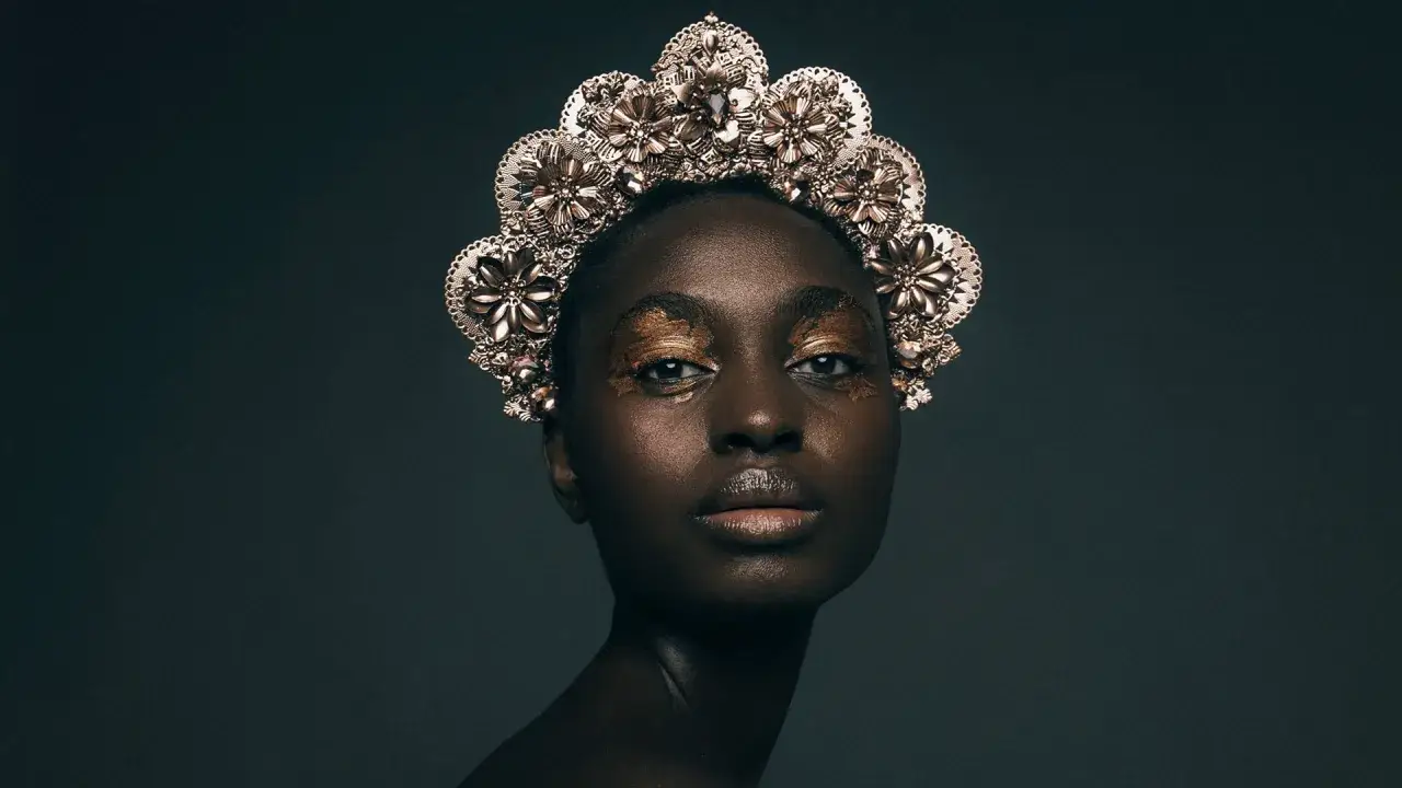 Portret kobiety w złotej koronie i makijażu oczu, wykonany techniką fotografia cyfrowa.