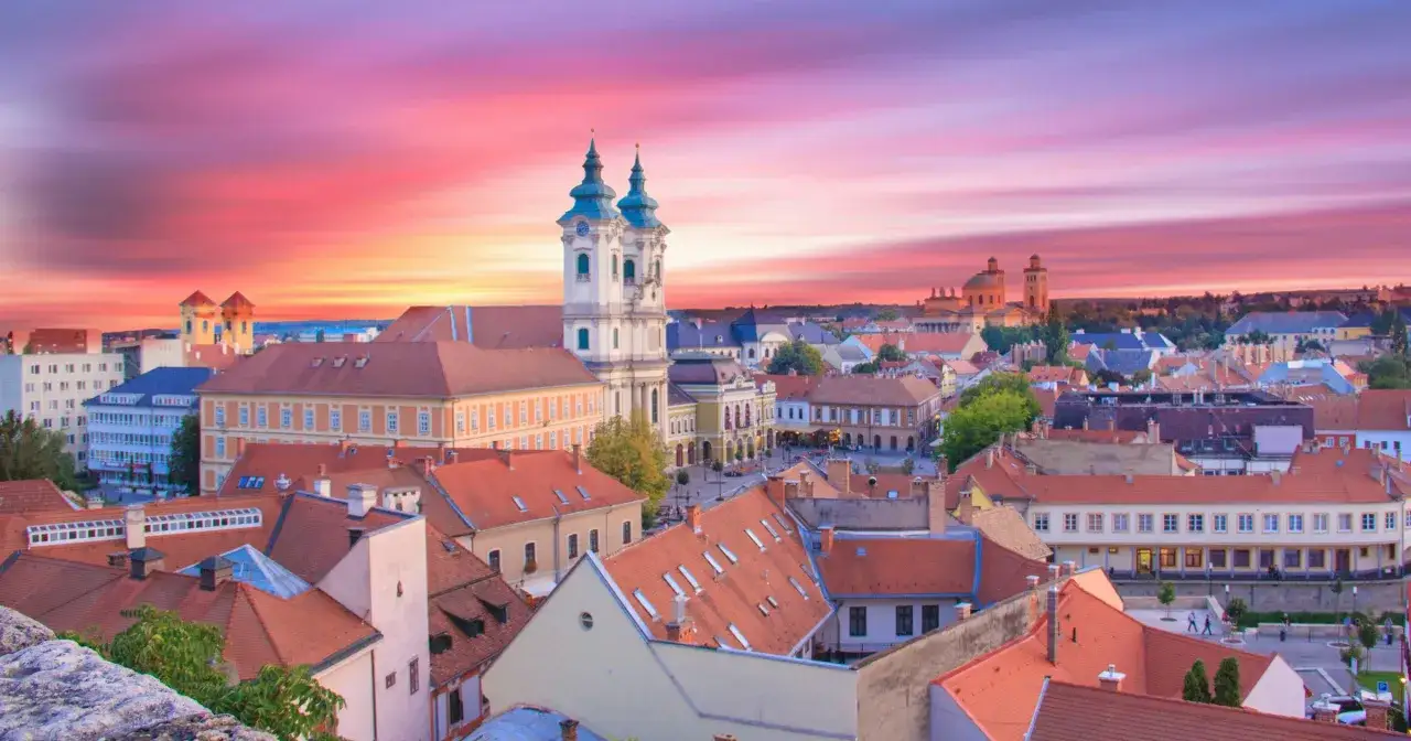 Eger i okolice atrakcje: malowniczy widok na miasto z charakterystyczną bazyliką i czerwonymi dachami o zachodzie słońca.
