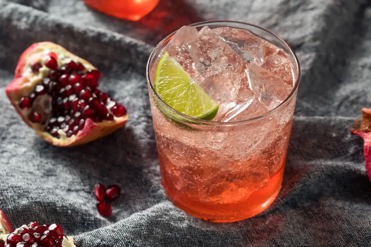 Erfrischender Drink mit Granatapfelkernen und Limette. Was ist Grenadine? Ein süßer Sirup, der oft für Cocktails verwendet wird.