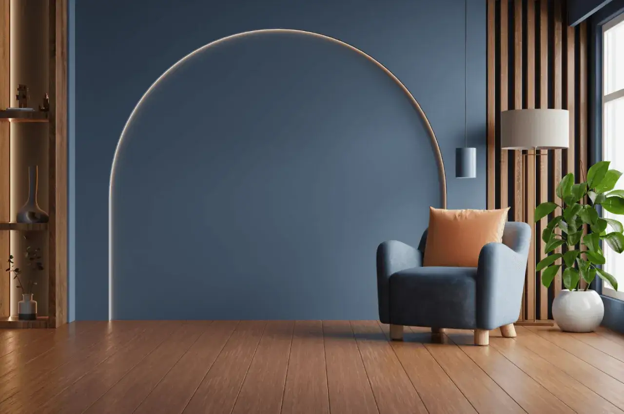 Un fauteuil bleu avec coussin orange, devant un mur bleu orné d'une arche lumineuse. Idéal pour savoir quel mur peindre en couleur.
