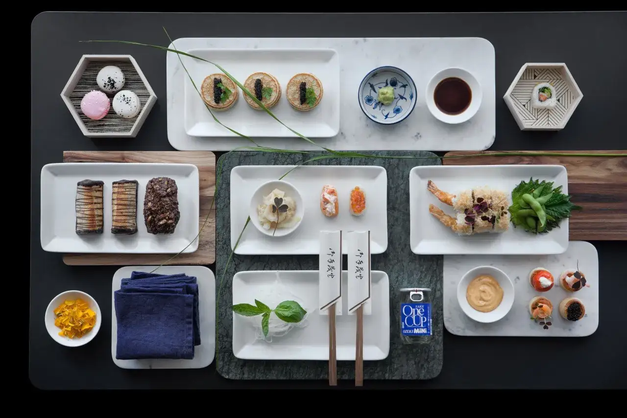 Elegancko podane przekąski, w tym mini naleśniki z kawiorem, sushi i makaroniki. Idealne inspiracje, jak zrobić sushi i inne smakołyki.