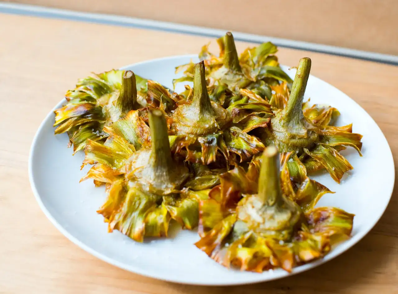 Carciofi fritti croccanti su un piatto bianco, un'ottima alternativa per chi sceglie di non mangiare carne.