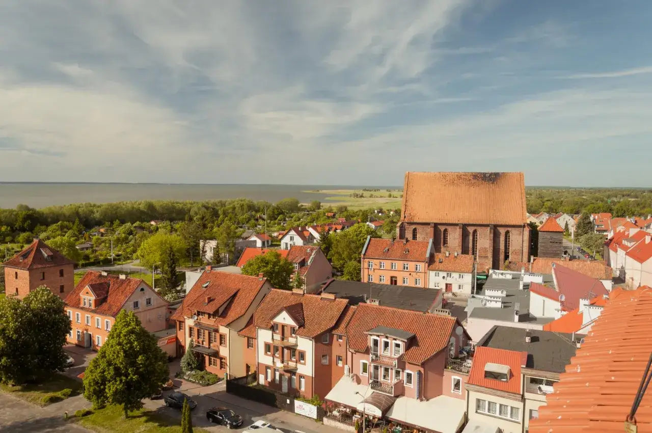 Widok na Frombork z dachu. Miasto z czerwonymi dachami, kościołem i jeziorem w tle. Idealne miejsce na wakacje z rodziną, mnóstwo atrakcji dla dzieci.