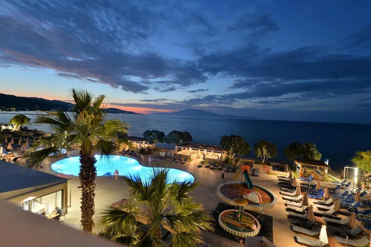Zachód słońca nad morzem, basen i palmy przy Alykanas Beach Hotel.
