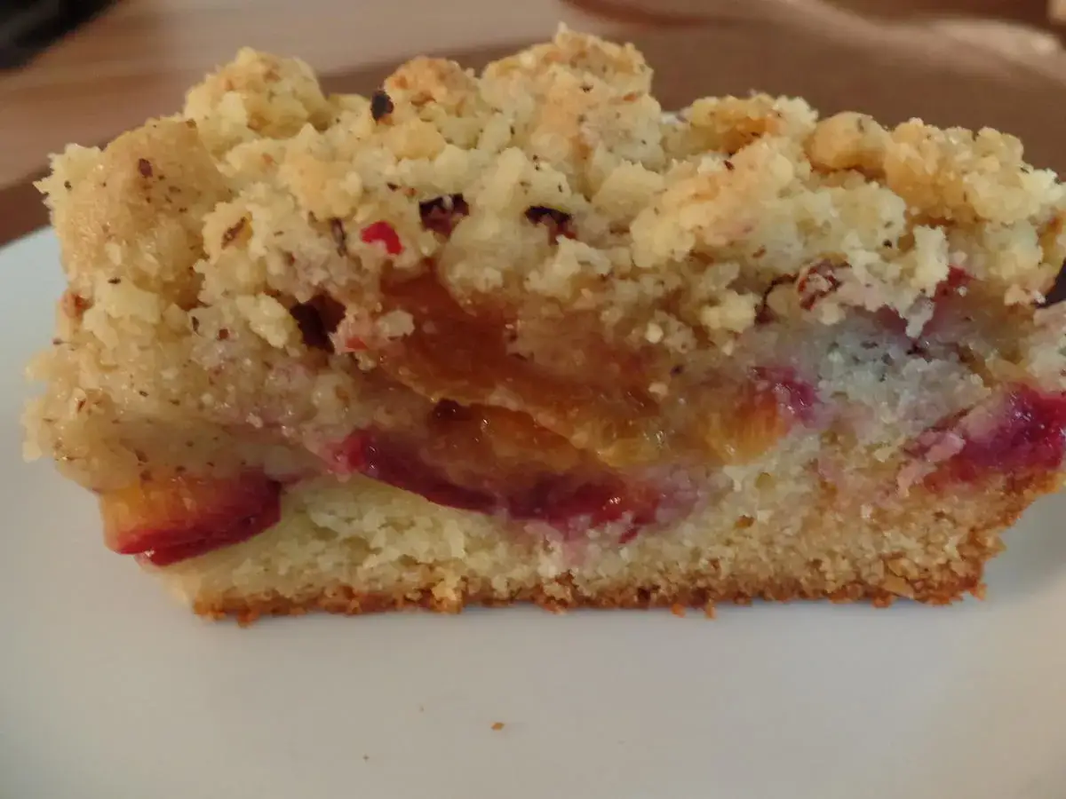 Ein Stück Apfel Pflaumen Kuchen mit Streuseln. Saftige Früchte und knusprige Krümel auf einem lockeren Teig.