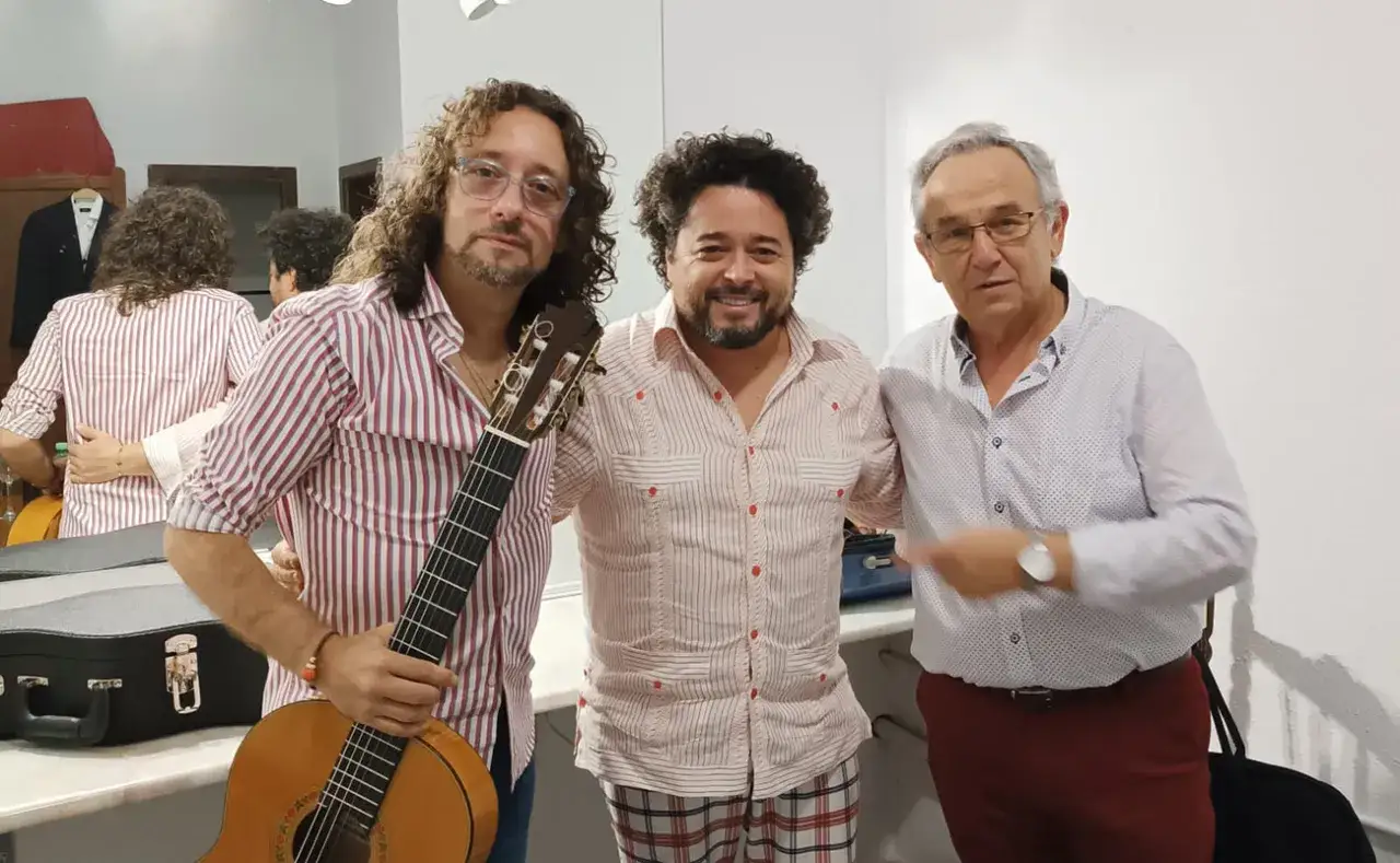 Tres hombres posan, uno con guitarra, listos para explorar los tipos de cante flamenco.