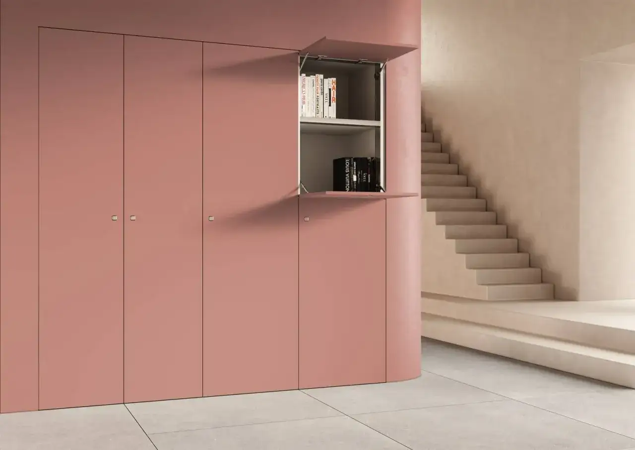 Armadio rosa con nicchia aperta che mostra libri. Soluzione elegante per come chiudere una nicchia nel muro.