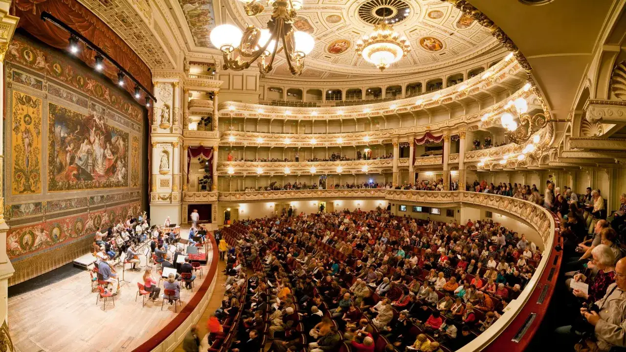Prunkvoller Opernsaal mit Orchester auf der B&uuml;hne und Publikum in Logen. Ein unvergesslicher oper jahr.