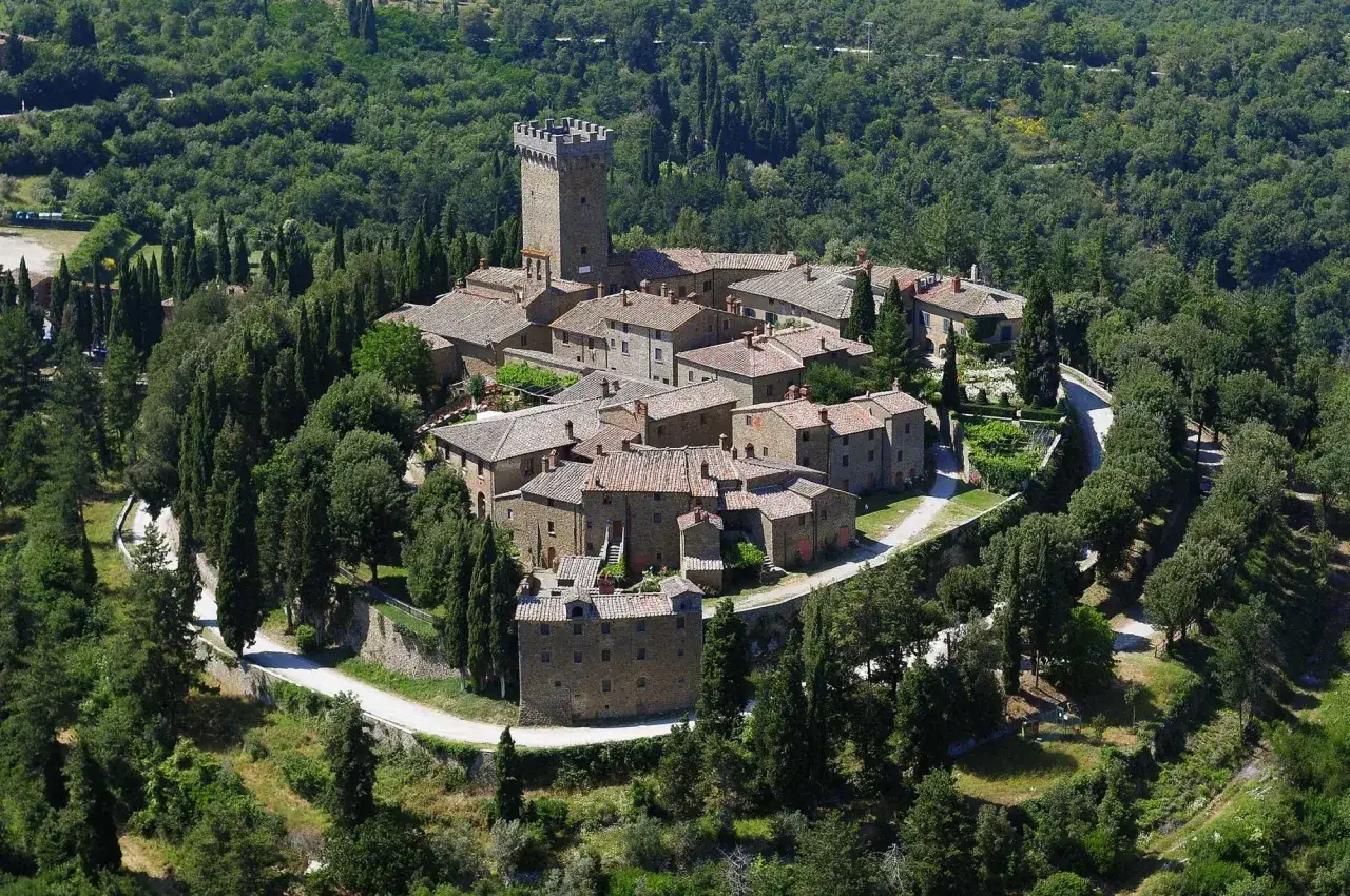 Il castello di Gargonza, un borgo medievale in pietra con una torre imponente, immerso nel verde della campagna toscana.
