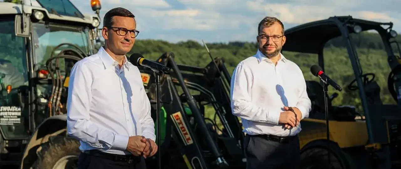 Mateusz Morawiecki i minister rolnictwa na tle maszyn rolniczych, być może w dniu, kiedy podpisano zielony ład.