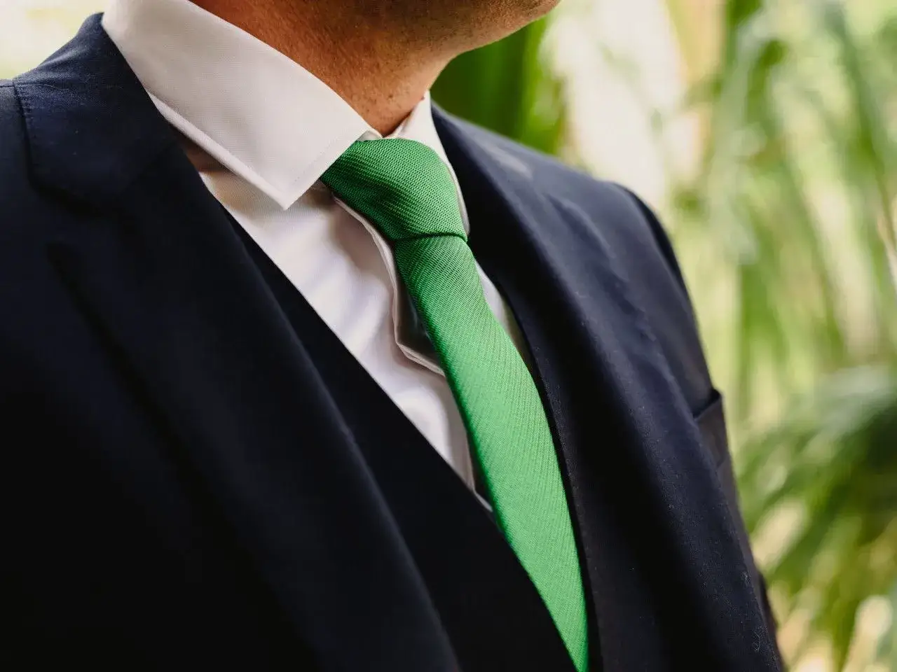 Elegancki mężczyzna w granatowym garniturze i białej koszuli, z zielonym krawatem. Idealna stylizacja, jeśli zastanawiasz się, jaki krawat do zielonego garnituru.