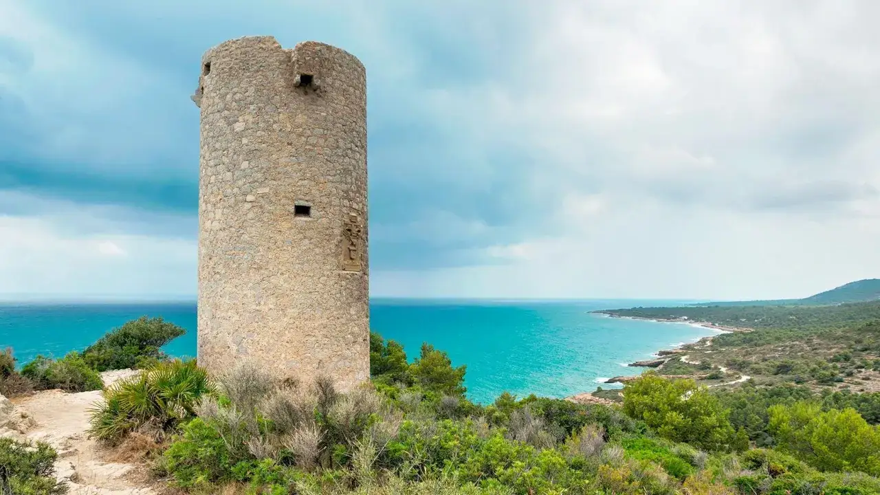 Torre defensiva en la playa del Russo, Pe&ntilde;&iacute;scola, con el mar turquesa y vegetaci&oacute;n mediterr&aacute;nea.