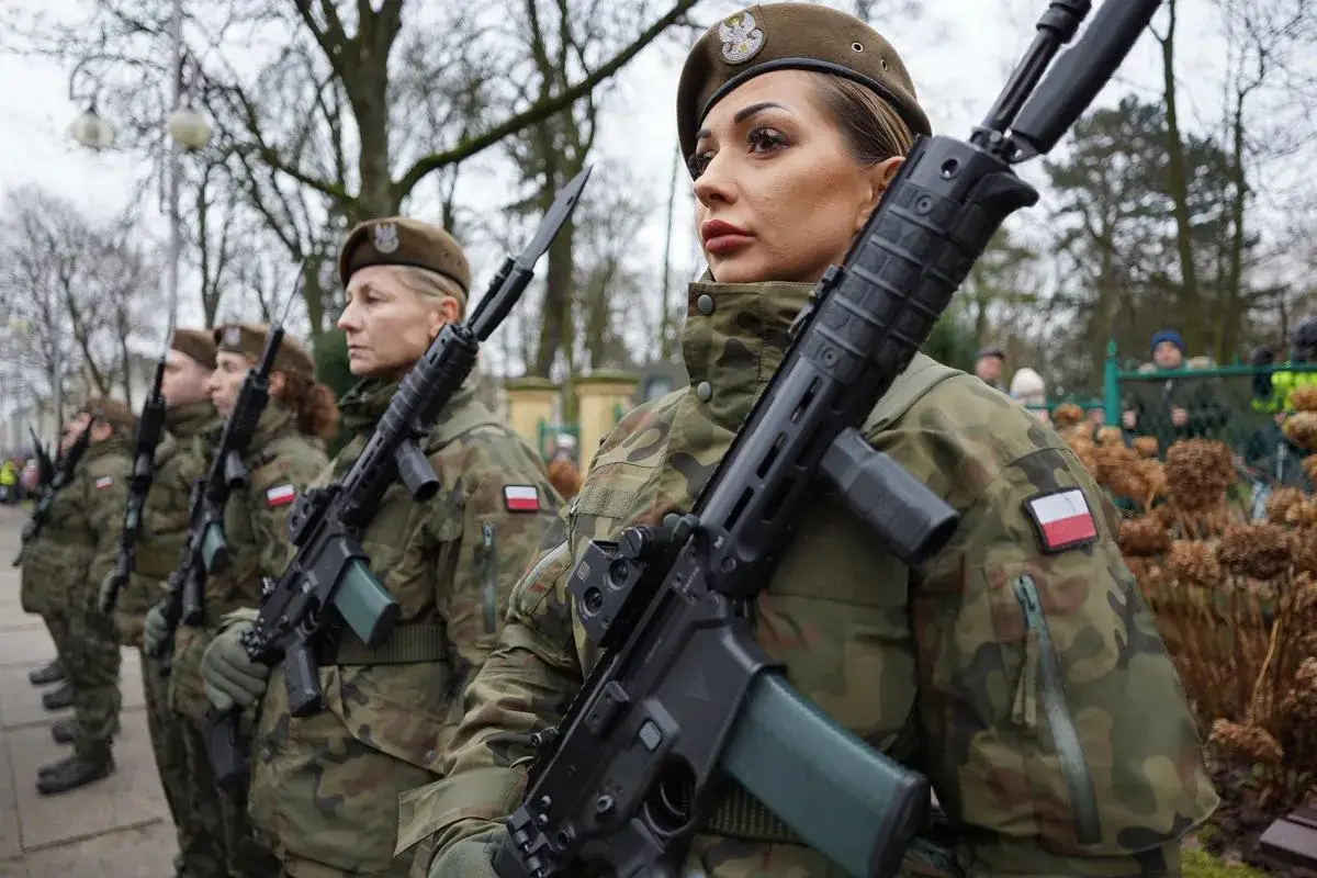 Kobiety w mundurach wojskowych z karabinami, gotowe do służby. Wiek poborowy w Polsce to ważny temat.